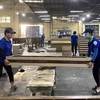 Công nhân Công ty Cổ phần Chế biến gỗ Thuận An kiểm tra các chi tiết khung giường gỗ. (Ảnh: Hồng Nhung/TTXVN) 