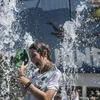 Người dân tránh nóng tại vòi phun nước ở Melbourne, Australia. (Ảnh: THX/TTXVN)