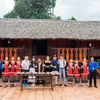 Nhóm các bạn trẻ Khanh Son Eco cùng đoàn khách du lịch chụp ảnh lưu niệm tại nhà dài của người đồng bào dân tộc Raglai, nhằm giới thiệu một sản phẩm văn hóa của huyện Khánh Sơn. (Ảnh: TTXVN phát)