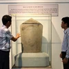 Cán bộ Bảo tàng tỉnh Ninh Thuận giới thiệu Bảo vật Quốc gia bia Hòa Lai. (Ảnh: Nguyễn Thành/TTXVN)