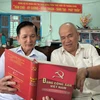 Ông Lê Văn Thiệm (bên trái) tại ấp 6, thị trấn Giồng Trôm (Bến Tre), Đảng viên 35 năm tuổi đảng trao đổi nghiên cứu văn kiện của Đảng với đảng viên trong chi bộ. (Ảnh: Huỳnh Phúc Hậu/TTXVN)