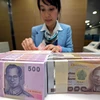 Nhân viên ngân hàng kiểm đếm đồng baht tại Bangkok, Thái Lan. (Ảnh: AFP/TTXVN)