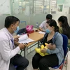 Phụ huynh đưa trẻ đi tiêm vaccine phòng bệnh sởi. (Ảnh: Đinh Hằng/TTXVN)