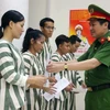 Đại tá Nguyễn Văn Viện, Phó Giám đốc Công an Thành phố Hà Nội trao Quyết định của Tòa án nhân dân thành phố về việc tha tù trước thời hạn có điều kiện cho các phạm nhân. (Ảnh: TTXVN)