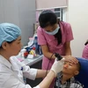 Bác sỹ khám cho trẻ có dị tật ở môi. (Ảnh: PV/Vietnam+)