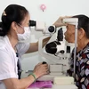 Nhân viên y tế khám mắt cho người dân. (Ảnh: TTXVN/Vietnam+)