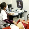 Nhân viên y tế siêu âm sàng lọc dị tật thai nhi cho thai phụ. (Ảnh: Dương Ngọc/TTXVN)