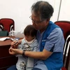 Giáo sư phẫu thuật thẩm mỹ Oh KapSung khám cho một bệnh nhi có 6 ngón tay. (Ảnh: PV/Vietnam+)