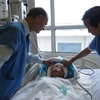 Giáo sư Nguyễn Thanh Liêm thăm khám cho một bệnh nhân sau phẫu thuật. (Ảnh: PV/Vietnam+)