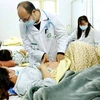 Phó giáo sư Đỗ Duy Cường khám cho một thai phụ mắc bệnh sởi. (Ảnh: PV/Vietnam+)