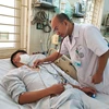 Tiến sỹ Lê Xuân Luật khám cho bệnh nhân điều trị sốt xuất huyết tại Trung tâm Nhiệt đới. (Ảnh: T.G/Vietnam+)