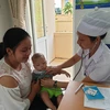 Nhân viên y tế chăm sóc sức khỏe cho trẻ nhỏ. (Ảnh: PV/Vietnam+)