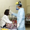 Nhân viên y tế kiểm tra thân nhiệt cho bệnh nhân được cách ly tại Trung tâm y tế huyện Bình Xuyên, tỉnh Vĩnh Phúc. (Ảnh: Dương Ngọc/TTXVN)