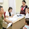 Bác sỹ Nguyễn Việt Hoa (bên phải) khám cho bệnh nhân nhi. (Ảnh: PV/Vietnam+)