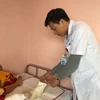 Bác sỹ Hoàng thăm khám chân cho cháu bé. (Ảnh: PV/Vietnam+)