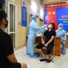 Nhân viên y tế quận Ba Đình lấy mẫu xét nghiệm cho các tiểu thương khu hải sản chợ Long Biên. (Ảnh: Thành Đạt/TTXVN)