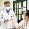 Phó giáo sư Nguyễn Mạnh Khánh thăm khám cho bệnh nhân sau phẫu thuật. (Ảnh: PV/Vietnam+)