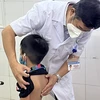 Bé trai bị gù vẹo cột sống được bác sỹ thăm khám. (Ảnh: PV/Vietnam+)