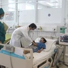 Bác sỹ Bệnh viện Đa khoa tỉnh Vĩnh Long thăm khám cho bệnh nhi bị sốc do sốt xuất huyết trong tình trạng nặng. (Ảnh: Lê Thúy Hằng/TTXVN)