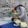 Bác sĩ Bệnh viện Sản-Nhi Kiên Giang khám, điều trị cho trẻ sốt xuất huyết. (Ảnh: Lê Huy Hải/TTXVN)