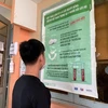 Các bạn trẻ đọc thông tin tuyên truyền về phòng chống HIV/AIDS và công tác điều trị. (Ảnh: T.G/Vietnam+)