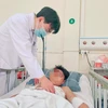 Phó giáo sư Phùng Duy Hồng Sơn thăm khám cho bệnh nhân sau phẫu thuật. (Ảnh: PV/Vietnam+)