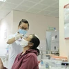 Nhân viên y tế lấy mẫu xét nghiệm cho người dân tới khám. (Ảnh: TTXVN/Vietnam+)