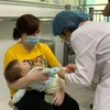 Bác sỹ kiểm tra sức khoẻ cho trẻ mắc bệnh tay chân miệng tại Bệnh viện Nhi Trung ương. (Ảnh: PV/Vietnam+)