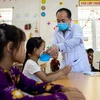 Cán bộ y tế phát khẩu trang cho các em học sinh tại Trường Phổ thông dân tộc bán trú Tiểu học xã Khâu Vai (Mèo Vạc, Hà Giang). (Ảnh: Nam Thái/TTXVN)