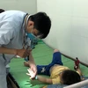 Bác sỹ thăm khám cho trẻ mắc bệnh tay chân miệng. (Ảnh: TTXVN/Vietnam+)