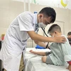 Bác sỹ tại Bệnh viện Đa khoa Xanh Pôn khám, theo dõi sức khỏe cho một trẻ mắc bệnh tay chân miệng. (Ảnh: T.G/Vietnam+)