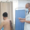 Phó giáo sư Nguyễn Hồng Hà thăm khám cho bệnh nhân sau phẫu thuật. (Ảnh: PV/Vietnam+)