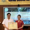 Phó giáo sư Đào Xuân Cơ trao giấy khen cho nữ điều dưỡng Đặng Thị Hạ. (Ảnh: PV/Vietnam+)