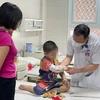 Bác sĩ Nguyễn Đức Lân - Trưởng khoa Ngoại nhi tổng hợp thăm khám cho bệnh nhi C. trước khi xuất viện. (Ảnh: PV/Vietnam+) 