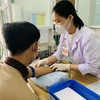 Nhân viên y tế tại Trung tâm Y tế thành phố Long Xuyên lấy máu xét nghiệm HIV cho người dân. (Ảnh: PV/Vietnam+)