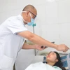 Phó giáo sư Nguyễn Hồng Hà kiểm tra mắt cho nữ bệnh nhân. (Ảnh: PV/Vietnam+)