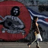Một phụ nữ đi bức graffiti của Che Guevara và lá cờ Cuba trên đường phố thủ đô La Habana. (Nguồn: Reuters)