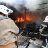 Lính cứu hỏa dập lửa đám cháy khu chợ ở Donetsk sau vụ pháo kích. (Nguồn: AFP/TTXVN)