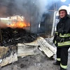 Lính cứu hỏa dập lửa đám cháy khu chợ ở Donetsk sau vụ pháo kích. (Nguồn: AFP/ TTXVN)