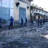 Hàng chục công nhân thay phiên nhau đào xới, dọn dẹp những nơi lũ bùn càn quét. (Ảnh: Minh Sơn/Vietnam+)