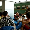 Cán bộ Ga Hà Nội nhắc nhở hành khách hút thuốc đúng nơi quy định. (Ảnh: Dương Ngọc/TTXVN)