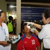 Bác sỹ Việt Nam và Lào đang tiến hành kiểm tra, mở băng mắt cho một bệnh nhân sau khi mổ. (Ảnh: Phạm Kiên/TTXVN)
