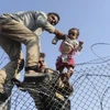 Người di cư Syria cố vượt qua hàng rào dây thép gai để vào lãnh thổ Thổ Nhĩ Kỳ. (Nguồn: AFP/TTXVN)