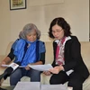 Bà Trần Tố Nga (trái) và phóng viên TTXVN cùng xem tập hồ sơ tập hợp 20.000 chữ ký của người dân tỉnh Sóc Trăng ủng hộ vụ kiện da cam. (Ảnh: Bích Hà/Vietnam+)