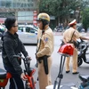 Cảnh sát giao thông tiến hành dừng xe, nhắc nhở học sinh phải đội mũ bảo hiểm khi tham gia giao thông. (Ảnh: Doãn Tấn/TTXVN)