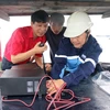 Lắp đặt máy ICOM cho các tàu cá. (Ảnh: Nguyễn Thanh/Vietnam+)