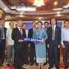 Bà Sunthone Saychac trao số tiền 257.000 USD cho Đại sứ Nguyễn Mạnh Hùng. (Ảnh: Nguyễn Chiến/Vietnam+)