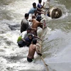 Người dân cố gắng vượt qua dòng nước lũ hoành hành tại Sedawatte, ngoại ô thủ đô Colombo, Sri Lanka. (Nguồn: EPA/TTXVN)
