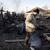 Người dân Ukraine thu dọn đống đổ nát của một ngôi nhà bị phá hủy sau vụ cháy nổ. (Nguồn: AFP/TTXVN)