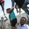 Người tị nạn Syria vượt qua hàng rào dây thép gai tại biên giới Thổ Nhĩ Kỳ. (Nguồn: AFP/TTXVN)